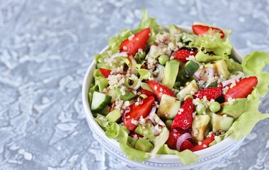 Fototapeta na wymiar Salad with strawberries, quinoa, avocado, cucumber, lettuce, onions and green peas. vegetarian food. Summer unusual salad. Exquisite salad with strawberries. Healthy diet and diet.
