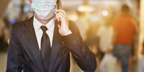 Close-up of businessman wearing face mask in black suit, Using smartphone to talking.