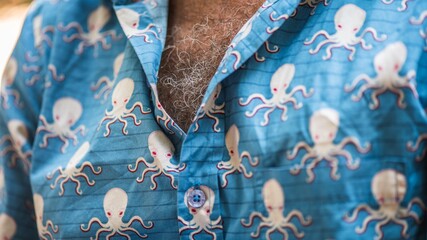 Close up shot of man's chest wearing a blue shirt with tiny illustrations of octopus on it