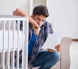Young man assembling baby bed with instruction manual