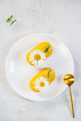 Raw cashew cakes decorated with chamomile flower on a white plate. Vertical orientation, top view. Sugar free, gluten, lactose.