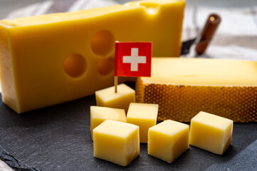 Swiss cheeses, block of medium-hard yellow cheese emmental or emmentaler with round holes and matured gruyere.