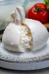 Eating of fresh handmade soft Italian cheese from Puglia, white balls of burrata or burratina cheese made from mozzarella and cream filling