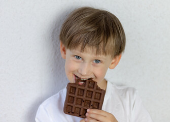 Cheerful boy with a chocolate waffle on a white background.