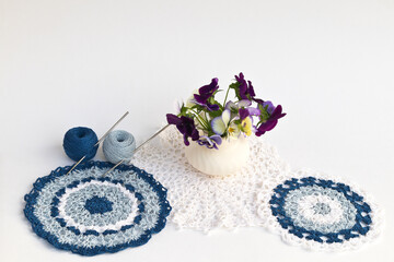 Summer still life with beautiful hand-knitted lace napkins, balls of cotton yarn, crochet hooks and...