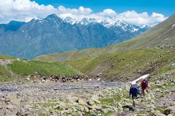 Fototapeta na wymiar Hiker on Mountain range on a hiking trail from Gergeti Trinity Church to Gergeti Glacier. a famous landscape in Kazbegi, Mtskheta-Mtianeti, Georgia.
