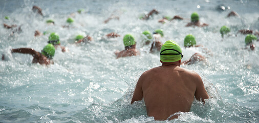 Competitors swimming out into open water at the beginning of triathlon - obrazy, fototapety, plakaty