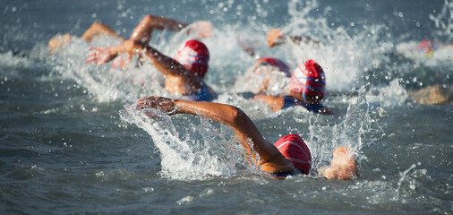 Wettkämpfer schwimmen zu Beginn des Triathlons ins offene Wasser