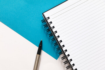 Flat lay of blank Notebook and pen on split color white and blue background. 