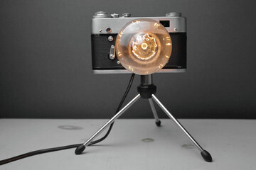 Retro lamp from an old camera with an Edison lamp on a gray background. Concept is a good idea.