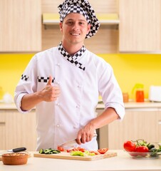 Young professional cook preparing salad at kitchen