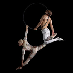A duet of acrobats performed aerial stunts on a suspension ring. Graceful performance of a woman...