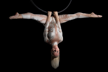 The acrobat performs the trick in a ring hanging in the air. A girl in a white suit hangs upside...