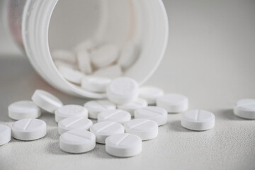 Close up of a white plastic jar with white tablets. Very close depth of field