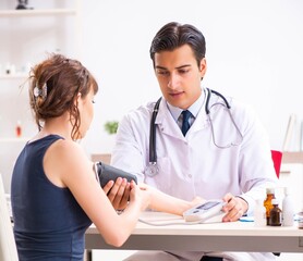 Young doctor checking woman's blood pressure
