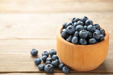 Blueberries in a bowl on grey wooden table with copy space.