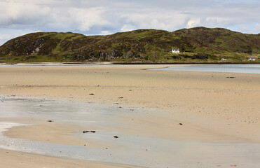 Large sandy beach on summers day Scottish Highlands Scotland with green hills and white cottages 
