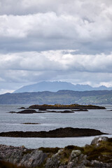 Distant mountain over the sea Scottish Highlands Scotland on a cloudy day with rocks in foreground  