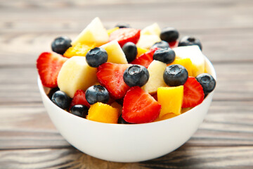 Salad with fresh fruits and berries on brown wooden background