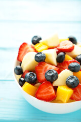 Fresh fruit salad in bowl on blue wooden background. Vertical foto