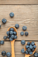 Fresh juicy blueberry fruits on a wooden spoons on grey background. Vertical foto
