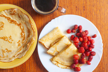 Breakfast on the table, pancakes with berries and coffee, top view