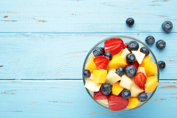 Salad with fresh fruits and berries on blue wooden background