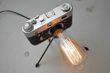 Retro lamp from an old camera with an Edison lamp on a gray background. Concept is a good idea.