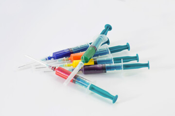 Syringes with multi-colored liquid on a white isolated background. Syringes of all colors of the rainbow.