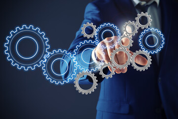 Businessman touching gear mechanism on dark background, closeup