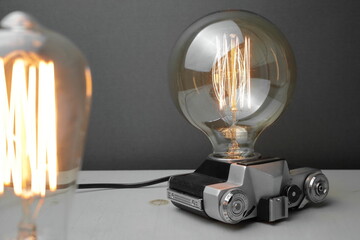 Retro lamp from an old camera with an Edison lamp on a gray background. Concept is a good idea.