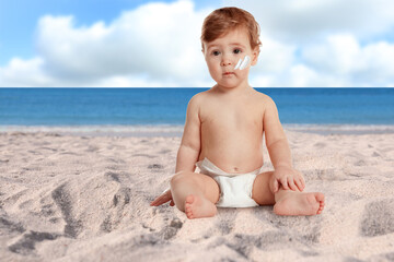 Fototapeta na wymiar Adorable baby with sun protection cream on face at sandy beach