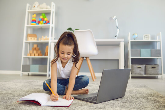 Online education of children. A little girl does a teacher lesson from a video lesson a distance learning web conference at home.