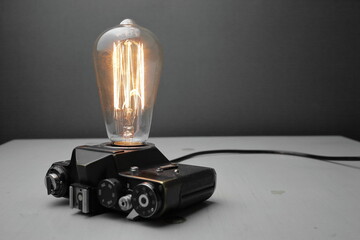 Retro lamp from an old camera with an Edison lamp on a gray background. Concept is a good idea.