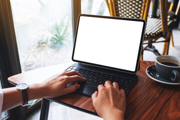 Mockup image of a woman typing on tablet keyboard with blank white desktop screen as a computer pc with coffee cup on the table
