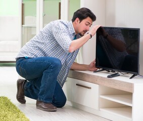Young man husband repairing tv at home