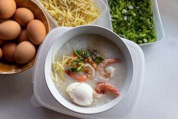 boiled rice soup with shrimp in white bowl on wooden table