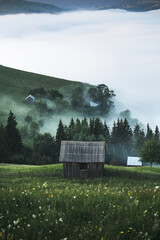 Beautiful view of small cabin surrounded by inversion fog in the wilderness after storm during...