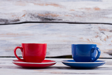 Red and blue coffee cups. Old white background.