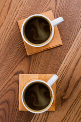 Topview two cups of coffee. Brown wooden table surface on the background.