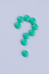 Question sign made of green round pills isolated on white. Pills medicine top view flat lay.