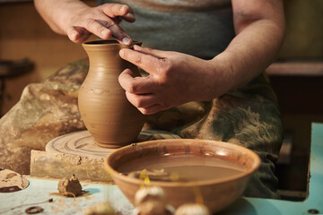 Process of making clay pot on potter's wheel in workshop. Potter at work