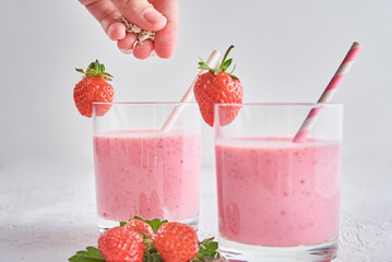 Strawberry milk shake in glass with straw and fresh berries on a white background