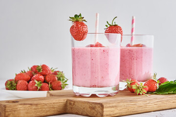 Strawberry milk shake in glass with straw and fresh berries on a white background