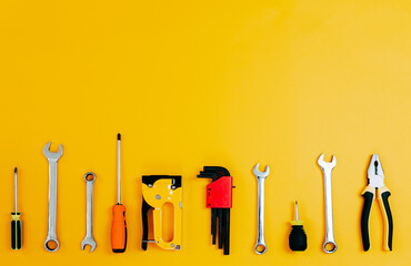 Tools top view on yellow background. Plier, open wrenches, screwdrivers and staple gun flat lay...