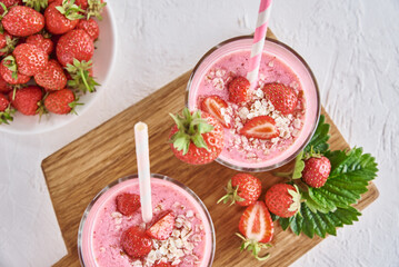 Strawberry milk shake in glass with straw and fresh berries on a white background