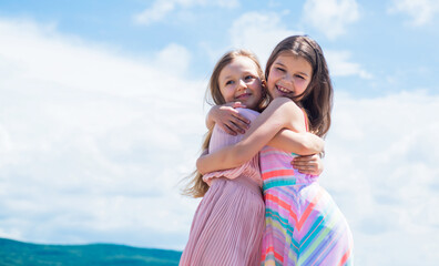 Fototapeta na wymiar small girls embrace. love and support. concept of sisterhood and friendship. family bonding time. best friends forever. two sisters on sky background. happy childhood. summer vacation