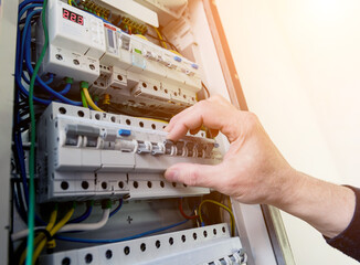 The man is repairing the switchboard voltage with automatic switches.