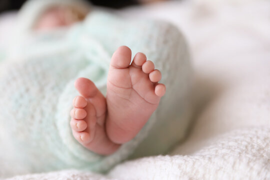Newborn baby lying on plaid, closeup of legs
