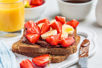 Toast with chocolate hazelnut spread,  banana and strawberries for breakfast. Breakfast food concept.